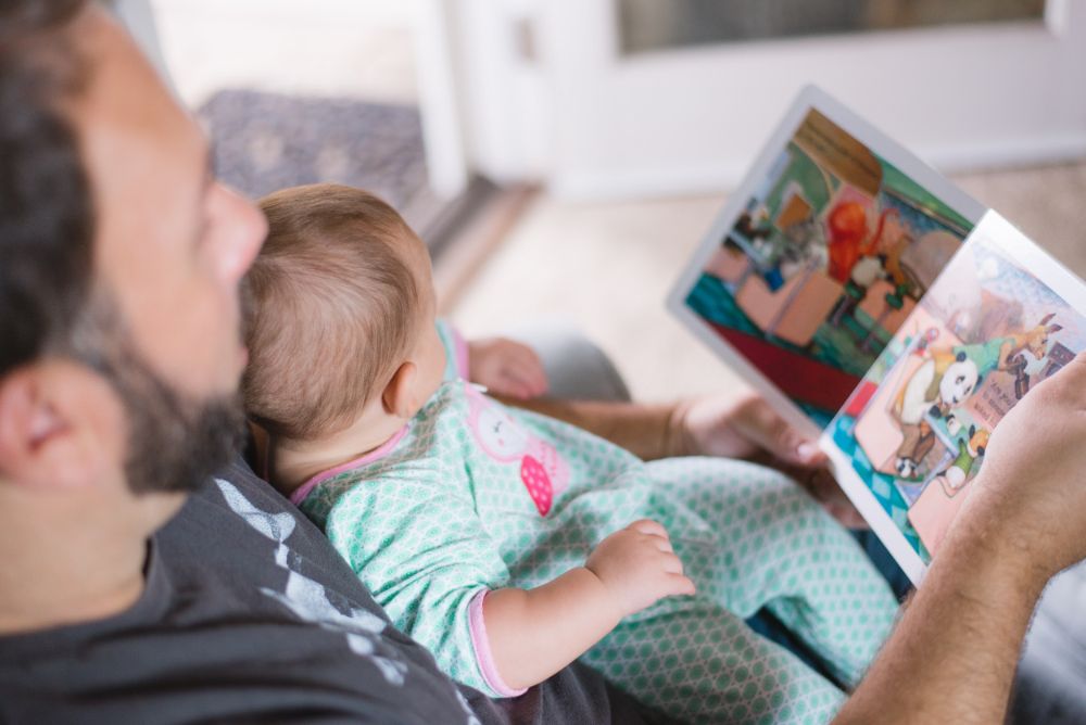 赤ちゃんに絵本を読んでいる男性